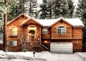 A log cabin with a front porch, a garage, and a snow-covered landscape. - Hikers Delight And Mountain Fun For You and Your Family! (South Lake Tahoe)