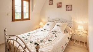 A bedroom with a bed, two bedside tables, a window, and wall art.