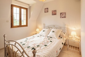Une chambre Ă coucher avec un lit, deux tables de chevet, une fenĂȘtre et des Ćuvres dâart murales.