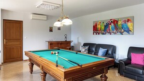 A pool table with balls, a sofa, a painting of parrots, and a door.