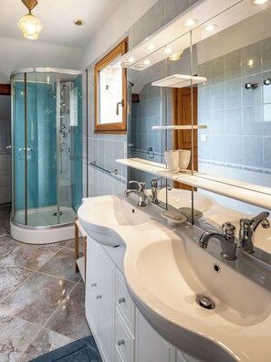 Une salle de bain moderne avec une douche Ă parois de verre, deux vasques, un grand miroir et un meuble en bois.