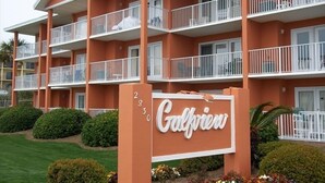 Ein mehrstöckiges Hotel mit Balkonen, einem Schild mit der Aufschrift "Gulfview" und gepflegter Bepflanzung.