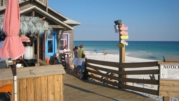 Ein Restaurant direkt am Strand mit einer Holzterrasse und einem Schild für 'Pompano Joes Seafood House'.