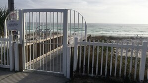 Ein verschlossener Eingang zu einem Strandbereich mit einem hölzernen Steg, der zum Ufer führt.