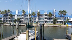 Ein Yachthafen mit vertäuten Booten, ein Gebäude mit blauen Dächern und Balkonen sowie Palmen.