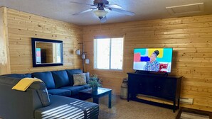 A cozy living room with a dark blue sofa, a small coffee table, and a television on a black stand.