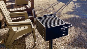 A deck with lounge chairs, a grill, and a Hillside Inn sign in a forested area.