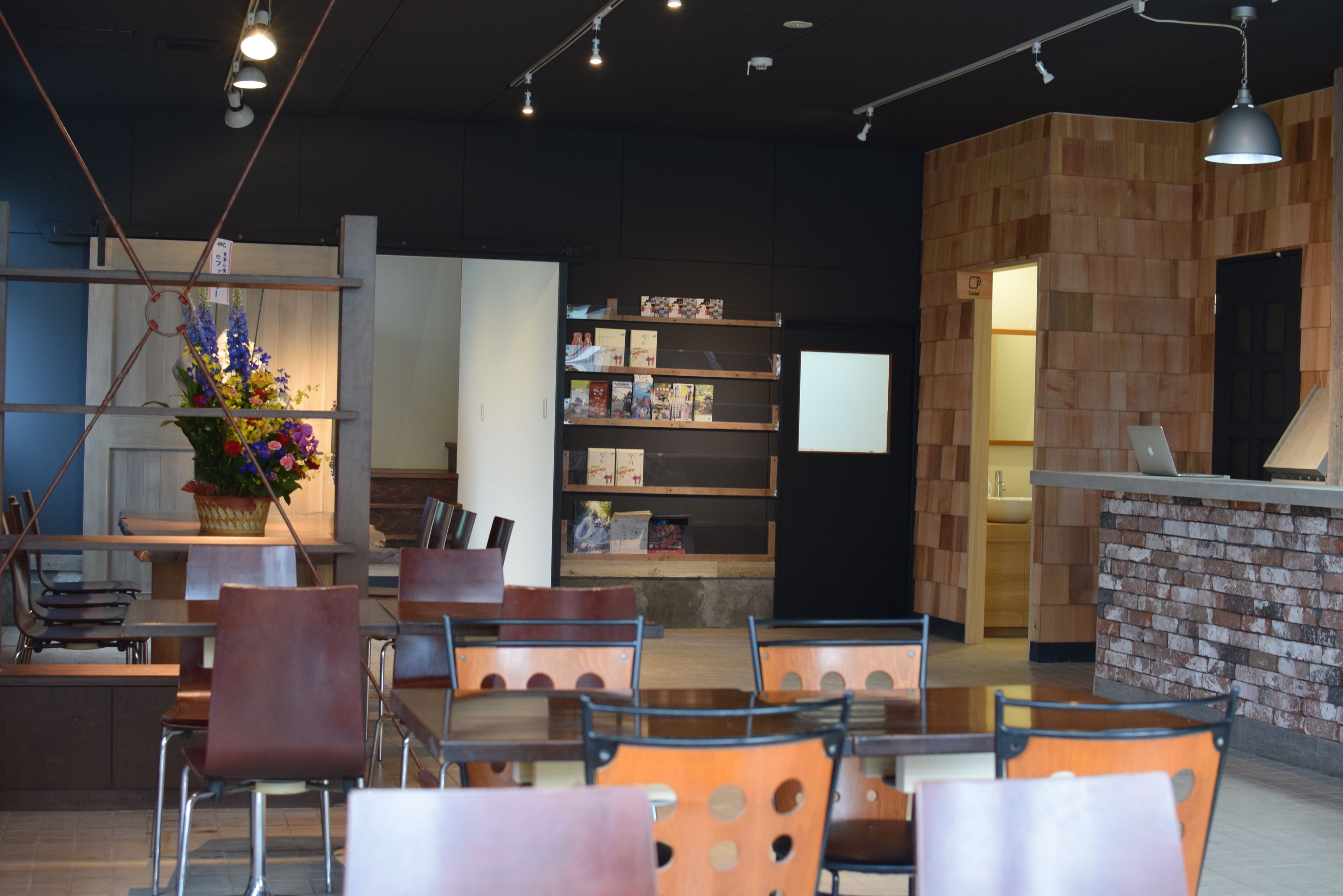 A modern interior with a reception desk, seating area, and a bookshelf.