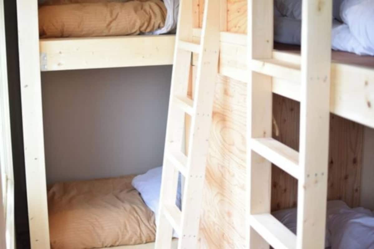 Habitación con literas de madera y una escalera.
