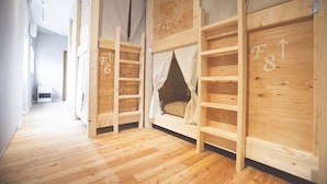 A room with bunk beds, wooden walls, and a wooden floor. - Noboribetsu Guest House AKA & AO - Hostel (Noboribetsu)