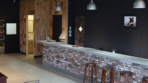 A modern bar area with a brick wall, wooden stools, and pendant lighting. - Noboribetsu Guest House AKA & AO - Hostel (Noboribetsu)