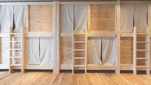 A room with wooden flooring and built-in shelving units with curtains. - Noboribetsu Guest House AKA & AO - Hostel (Noboribetsu)