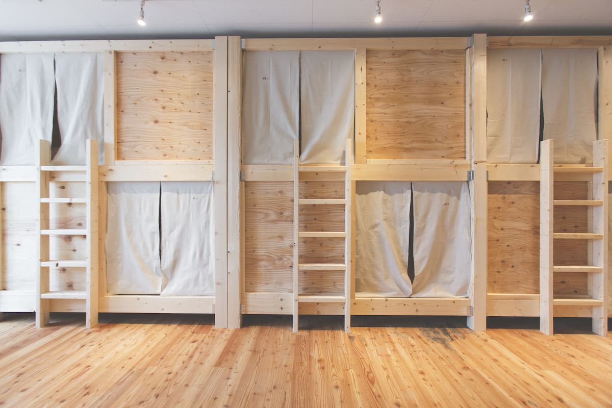 Una habitación con suelo de madera y estanterías empotradas con cortinas.