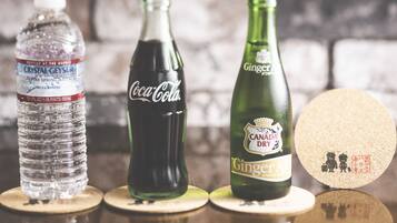 Three bottles of beverages on wooden coasters.