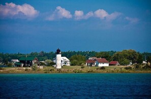 Une ville côtière dotée d’un phare, de maisons et offrant une vue dégagée sur l’eau.