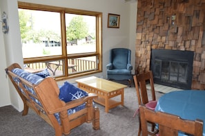 Relax in this inviting living room with a fireplace, wooden bench, and large window offering a view of the outdoors.