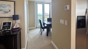 A modern kitchen with a built-in refrigerator and a water dispenser. A dining area with a table and chairs is visible in the background. - Fantastic Penthouse Downtown Grand Haven! Harbor Front Views! Walk Everywhere! (Grand Haven)