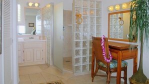 A bathroom with a glass shower enclosure, a wooden vanity, and a mirror with lights.