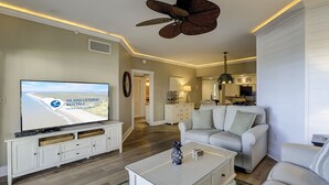 Una sala de estar con una televisión mostrando 'Island Getaway Rentals' y un ventilador de techo.
