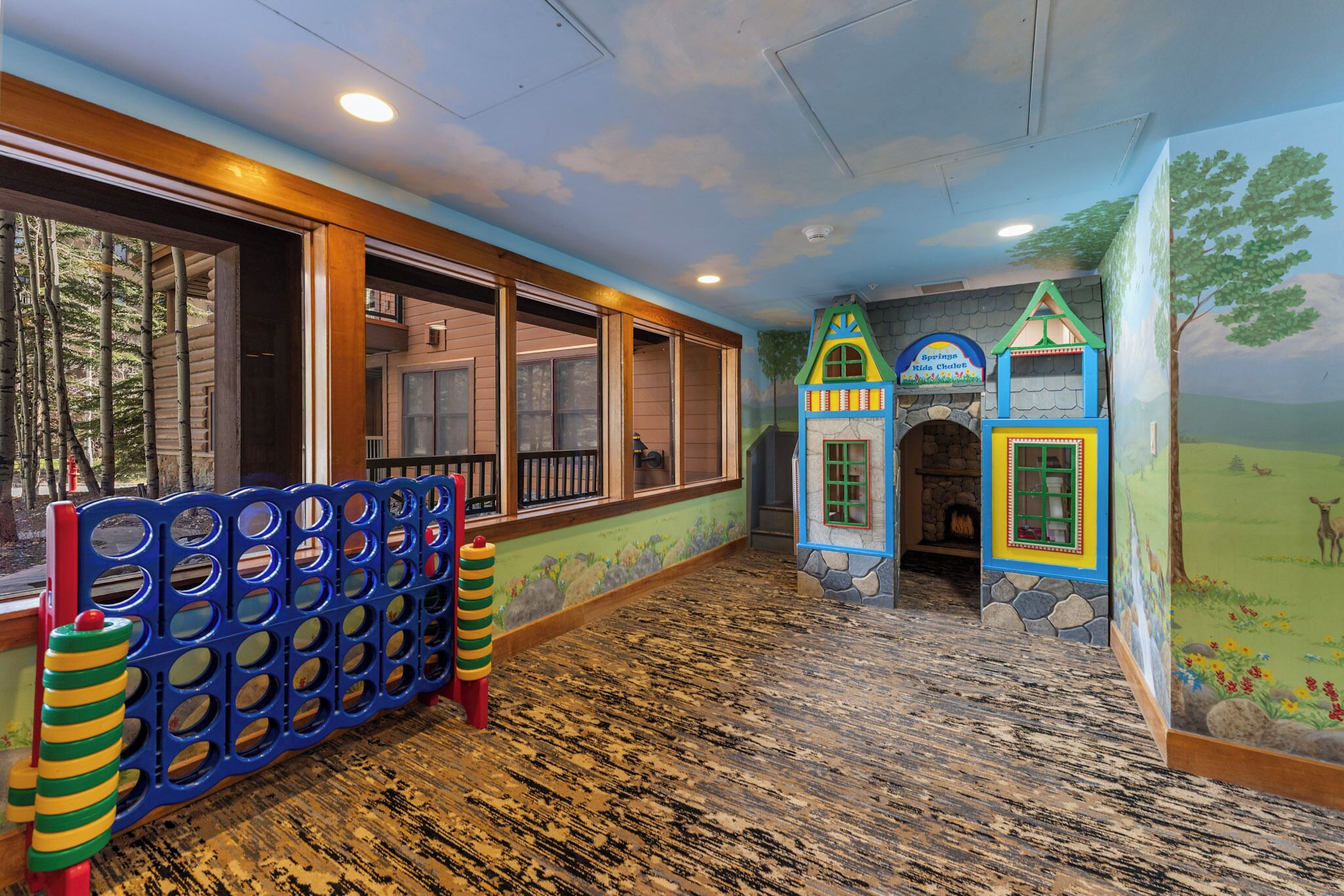 The on-site kids club features colorful play structures and a whimsical woodland mural, creating an imaginative space where your little ones can explore and play safely.