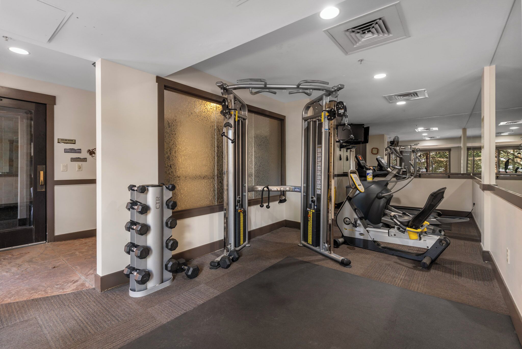 A gym with weight machines, a rowing machine, and dumbbells.