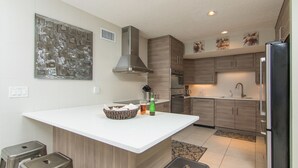 A modern kitchen with a central island, stainless steel appliances, and wooden cabinetry. - Oceanfront - 3 Bedroom Renovated 1,800 sq ft. + Huge Balcony -  Casual Elegance (St. Augustine Beach)