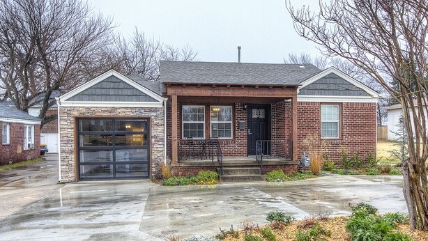 A two-story brick house with a front porch, a garage, and a driveway. - Charming Brick Home Off Of Route 66 Near Tulsa Expo Fairgrounds. Sleeps 8 (Tulsa)
