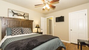 A bedroom with a bed, wooden headboard, ceiling fan, and a painting of an airplane. - Charming Brick Home Off Of Route 66 Near Tulsa Expo Fairgrounds. Sleeps 8 (Tulsa)