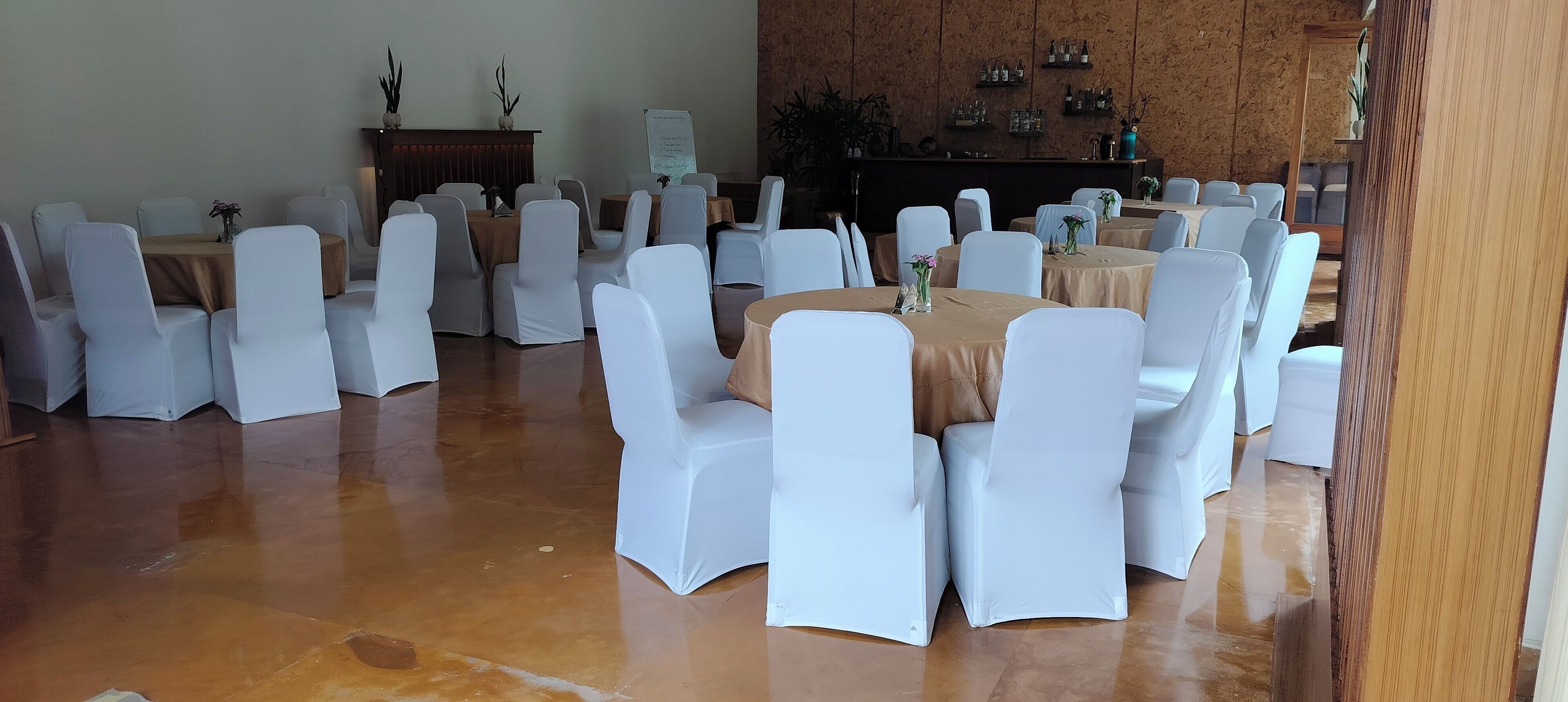 A conference room with multiple tables and chairs, a whiteboard, and a wooden wall with shelves.