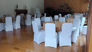 A conference room with multiple tables and chairs, a whiteboard, and a wooden wall with shelves.