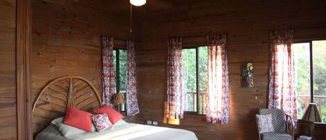 A wooden cabin bedroom with a bed, a chair, and a desk.