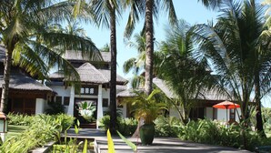 A resort with thatched-roof buildings, a wooden walkway, and lush tropical vegetation. - Yoma Cherry Lodge (Ngapali)