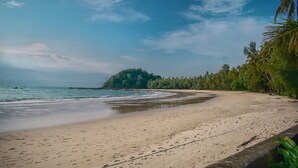 A beach with a sandy shore, a small island in the distance, and palm trees lining the beach. - Yoma Cherry Lodge (Ngapali)