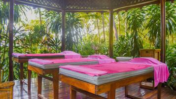 Relax in a serene spa setting surrounded by lush tropical vegetation and shaded by a wooden lattice roof.