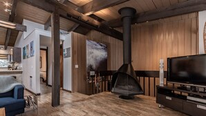 A modern living room with a large TV, wooden flooring, and a fireplace. - Walk to Village Gondola. Updated 4BR 3 Bath for 2 families. Sleep 10. Fireplace. (Mammoth Lakes)