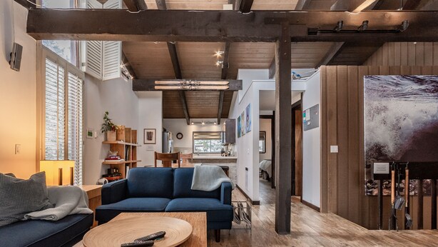 A modern living room with a blue sofa, wooden coffee table, and a painting on the wall. - Walk to Village Gondola. Updated 4BR 3 Bath for 2 families. Sleep 10. Fireplace. (Mammoth Lakes)