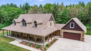 Une maison à deux étages dotée d’un patio couvert, d’un garage et d’une pelouse bien entretenue.