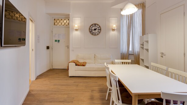 Un salon moderne avec un canapé blanc, une table à manger en bois et une horloge murale.