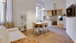 Une cuisine moderne avec des meubles blancs, une table à manger avec des chaises et un four encastré.