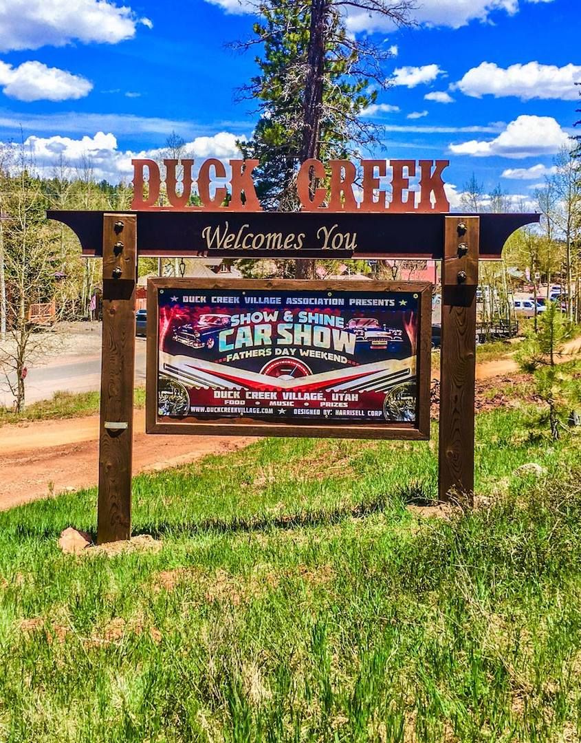 A welcome sign for Duck Creek Village, Utah, advertising a car show and Father's Day weekend event.