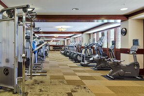 Une salle de sport équipée de machines de cardio, de machines de musculation et dotée d’un mur recouvert de miroirs.