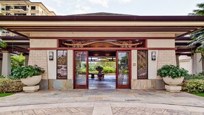 A hotel entrance with a covered walkway, large potted plants, and a stone-tiled floor. - Relaxing 4th floor with Lap Pool View - Ocean Tower Beach Villa (Kapolei)