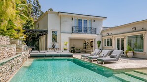 A modern house with a swimming pool, outdoor seating, and a balcony.