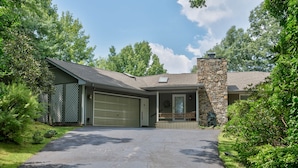A two-story house with a stone chimney, a garage, and a covered porch. - Bella Regalo, Private 2BR, 2BA Mountain Escape, Upgraded with Panoramic Views (Pisgah Forest)
