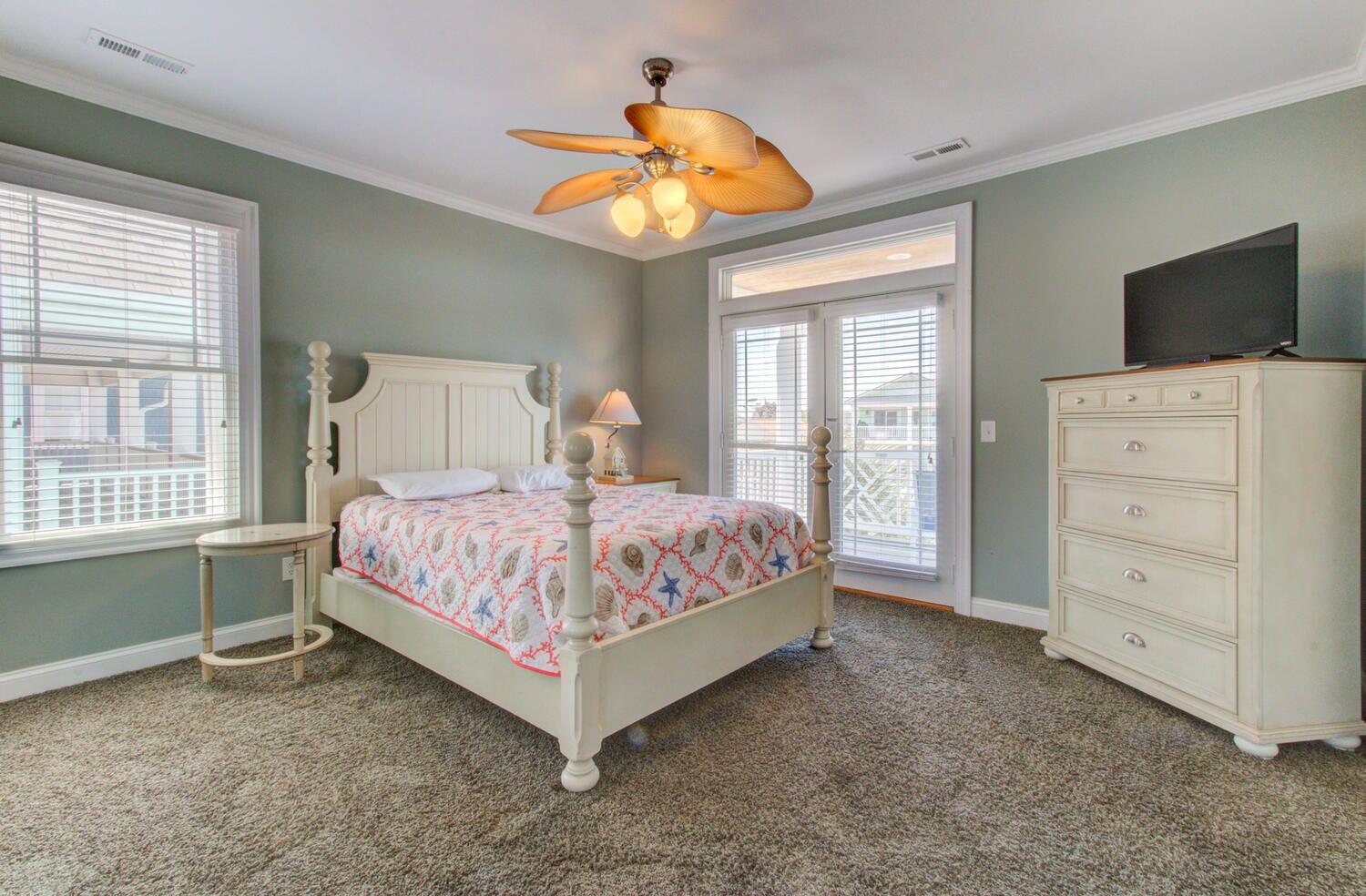 Une chambre à coucher avec un lit, une commode, un ventilateur de plafond et un téléviseur.