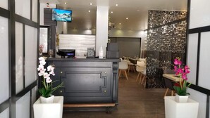 A hotel reception area with a modern design, featuring a reception desk, seating area, and decorative elements like orchids and a TV screen. - Hotel de la Gare (Modane)