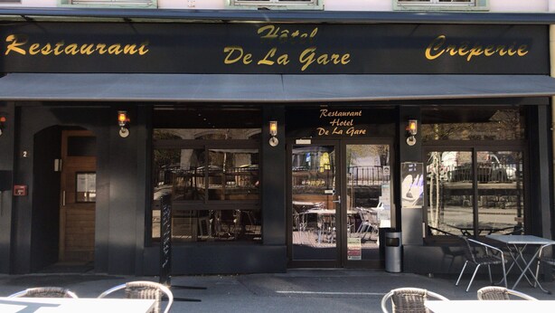The exterior of a restaurant named 'De La Gare' with outdoor seating and a view of the street. - Hotel de la Gare (Modane)