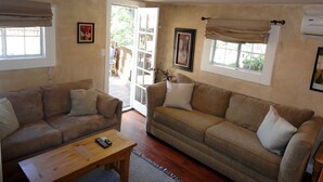 A living room with two sofas, a coffee table, and a sliding glass door leading to an outdoor area. - Woodland Hills Cottage (Woodland Hills)