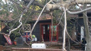 A stone wall, a red door, and a white outdoor seating area. - Woodland Hills Cottage (Woodland Hills)