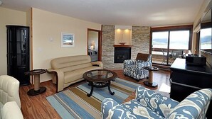 A living room with a fireplace, a sofa, a coffee table, and a view of the outdoors. - Amazing Mountain & Lakefront Views- Special!  1 FREE nite w/ 7 nite booking (Dillon)